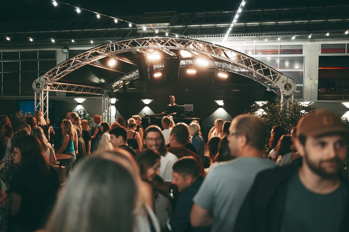 DJ-Auftritt auf der Terrasse unter beleuchtetem Traversenbogen bei Nacht